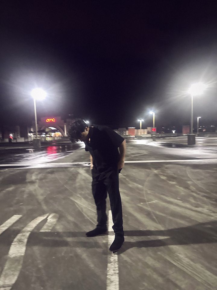 YNGM0M0 in all black in an empty parking lot at night